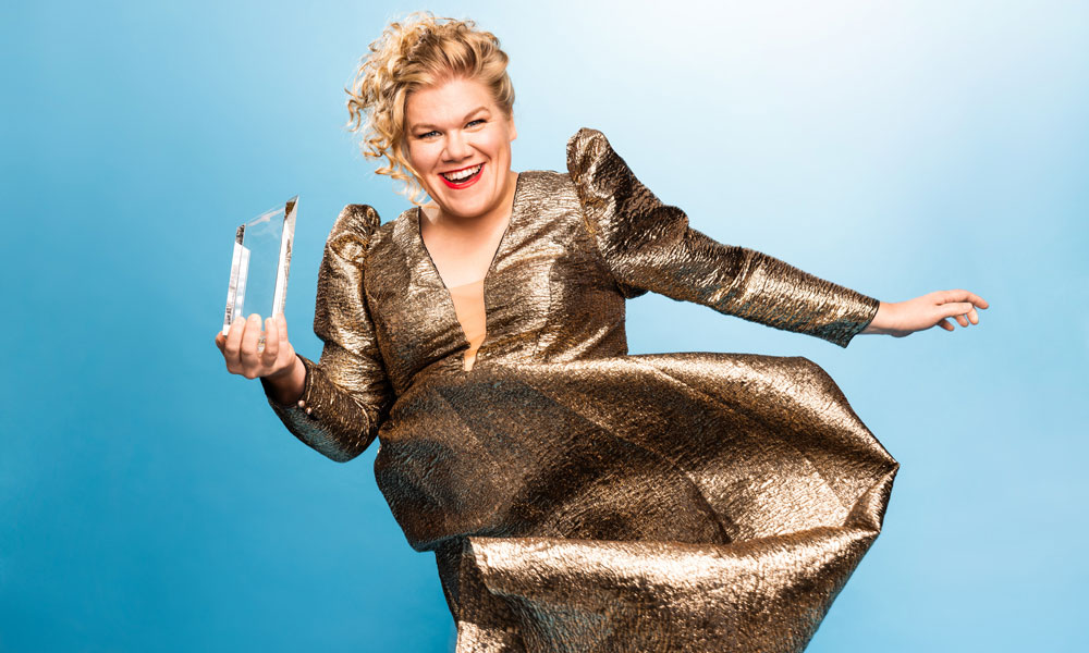 Foto von Gisa Flake in goldenem Kleid die den Pokal hält