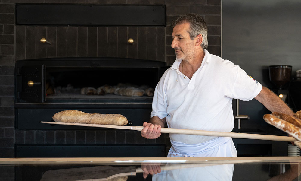 Bäcker holt Brot aus dem Holzofen