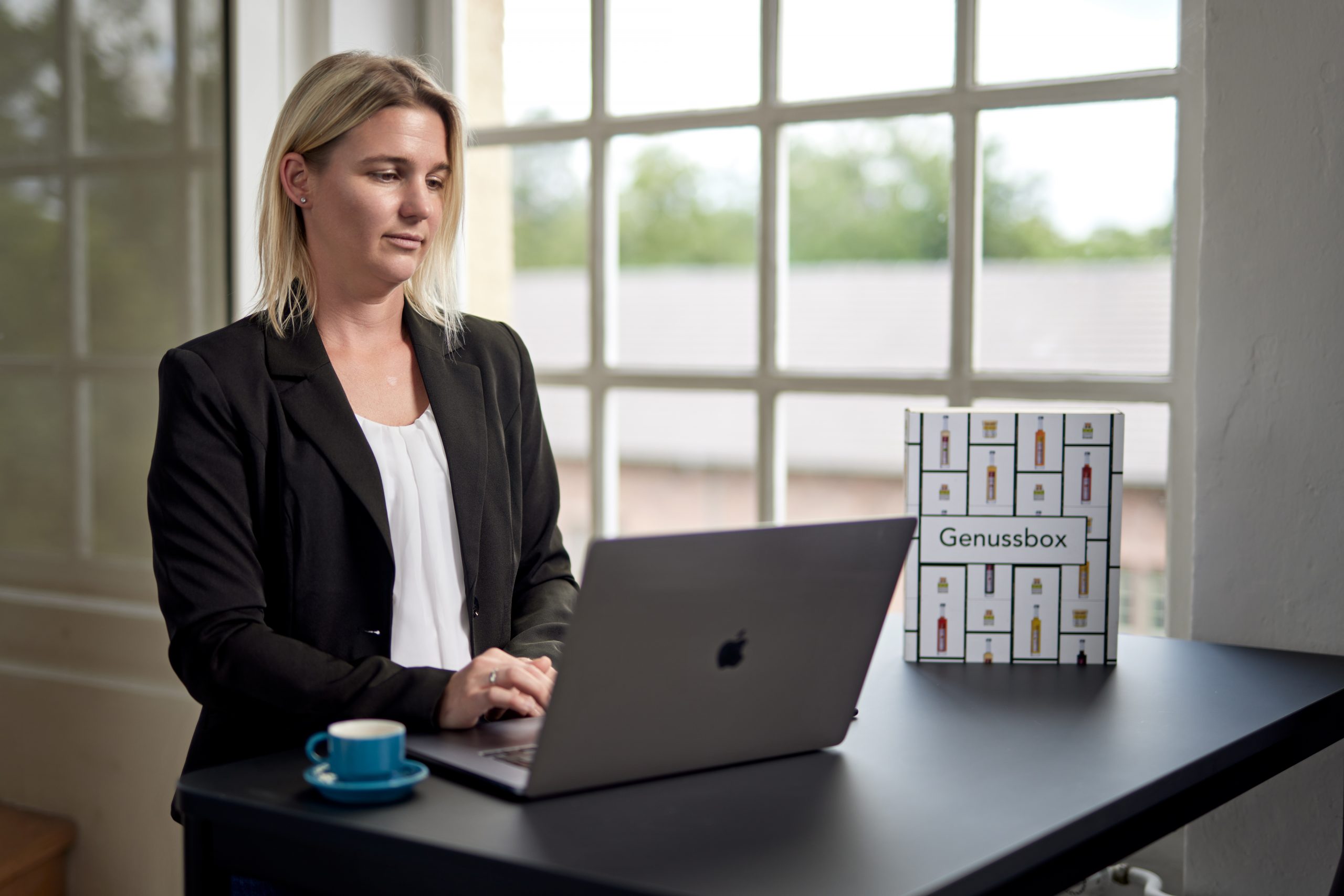 Jessica Deutsch arbeitet am Laptop an einem Schreibtisch in einem hellen Raum.