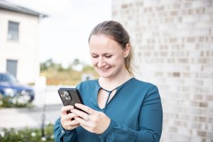 Saskia Richardsen mit Smartphone in der Hand beim Arbeiten an Social-Media-Content
