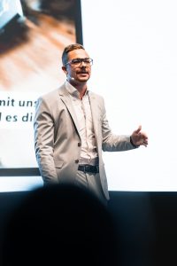 Manuel Spors steht auf der Bühne bei einer Keynote:Umgang mit Beschwerden