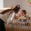 Übergangseinrichtung beatmete Kinder Deutschland Mutter beugt sich fürsorglich zu ihrem beatmeten Kleinkind im Gitterbett – Alltag mit außerklinischer Intensivpflege