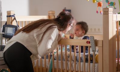 Übergangseinrichtung beatmete Kinder Deutschland Mutter beugt sich fürsorglich zu ihrem beatmeten Kleinkind im Gitterbett – Alltag mit außerklinischer Intensivpflege