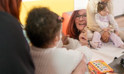 Frau von Haus Atemzeit spielt lachend mit einem beatmeten Kleinkind auf dem Boden – Begleitung im Alltag der Übergangseinrichtung Übergangseinrichtung für beatmete Kinder